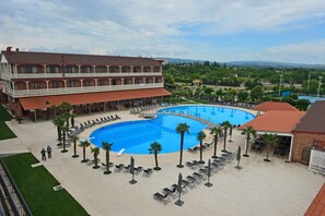 Un hotel con una amplia piscina, mobiliario exterior y vistas del paisaje circundante.