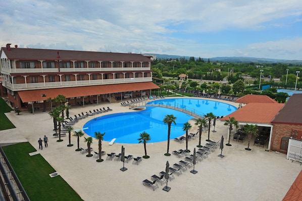 Un hotel con una amplia piscina, mobiliario exterior y vistas del paisaje circundante.