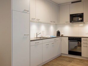 Una cocina moderna con armarios blancos, electrodomésticos de acero inoxidable y suelo de madera.