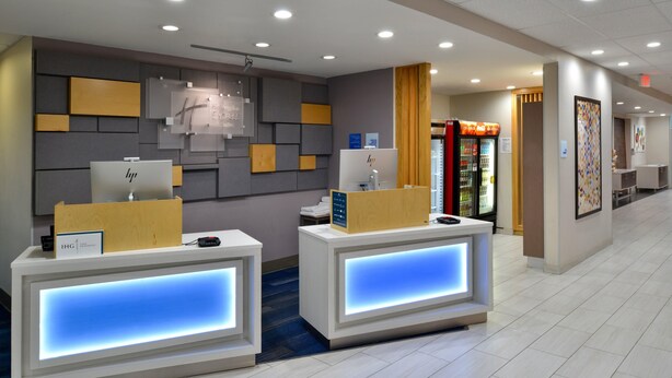 A hotel reception area with two reception desks, a wall-mounted clock, and a vending machine. - Holiday Inn Express and Suites Wylie West (Wylie)
