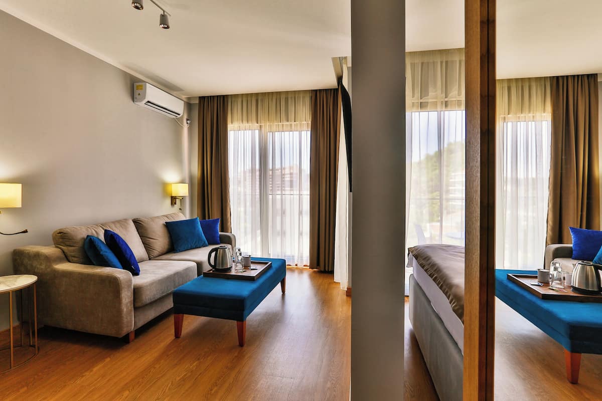 Une chambre d’hôtel équipée d’un canapé, d’une table basse, d’un lit et d’un bureau avec un plateau.