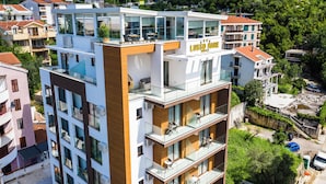 A modern hotel with multiple balconies, large windows, and a prominent sign.