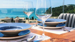 A table set with blue and white plates, two wine glasses, and cutlery, overlooking a coastal view. - Lusso Mare (Boreti)