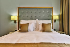 Una habitación de hotel con una cama grande, dos lámparas de noche y un cabecero.