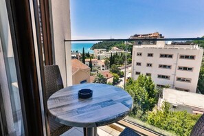 A balcony with a table and chair, overlooking a coastal cityscape with buildings and trees. - Lusso Mare (Boreti)