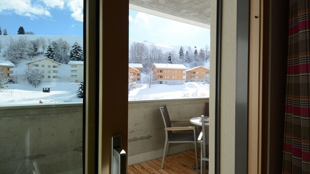 Un balcon avec un plancher en bois, une chaise et une table.