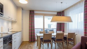 Une cuisine moderne dotée d’un four encastré et d’un coin repas avec une table et des chaises.