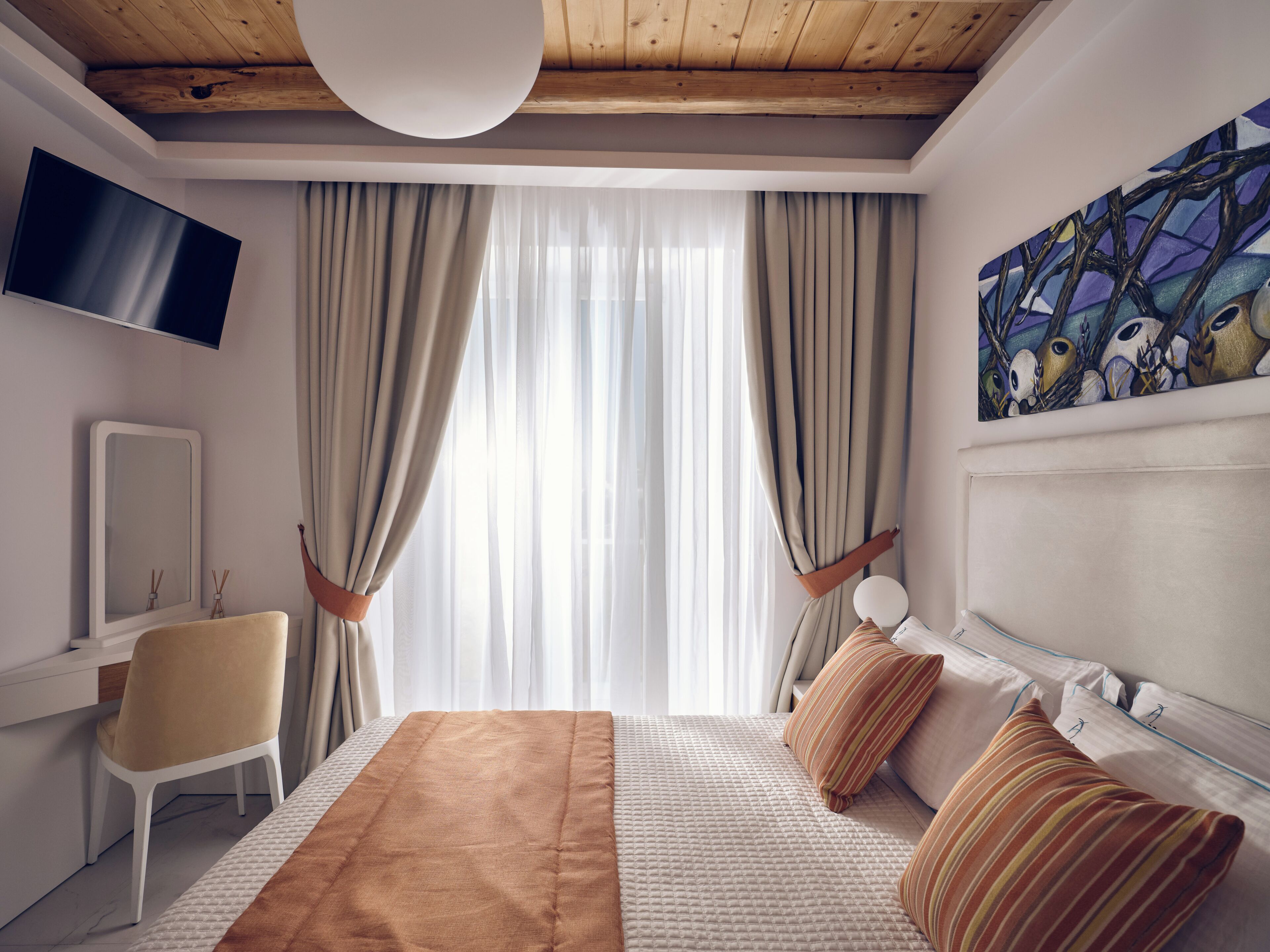 A modern hotel room with a large bed, a TV, a painting, and a desk.