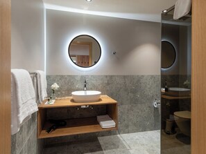 A modern bathroom with a round mirror, a wooden vanity, and a toilet. - Pradas Resort Brigels, (Breil/Brigels), 65055B by Interhome (Breil/Brigels)