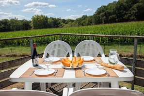 A table set for two with a bottle, wine glasses, plates, cutlery, a baguette, and a pitcher of water. - Olydea la Chalosse (Cassen)