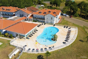 A large swimming pool with sun loungers and a covered area, surrounded by a fenced deck. - Olydea la Chalosse (Cassen)