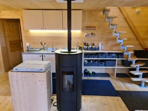Een compacte keuken met een centraal geplaatst fornuis, houten kastjes en een ingebouwde plank met diverse spullen.