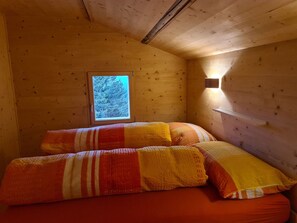 A small, cozy room with a single bed, a window, and a wall-mounted light fixture. - Maiensäss Tegia Cucagna, Rueun, (Rueun), 56001B by Interhome (Rueun)