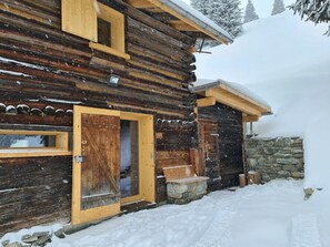 A log cabin with a wooden door, a window, and a stone wall. - Maiensäss Tegia Cucagna, Rueun, (Rueun), 56001B by Interhome (Rueun)
