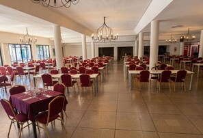 Un amplio comedor con varias mesas y sillas, candelabros y vistas al exterior.