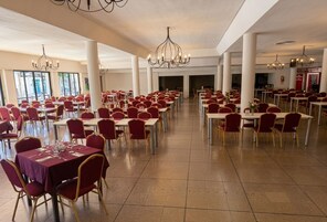 Un amplio comedor con varias mesas y sillas, candelabros y vistas al exterior.