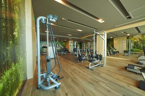 A gym with various exercise equipment, wooden flooring, and a large mirror. - Secrets Sunny Beach Resort & Spa (Nessebar)