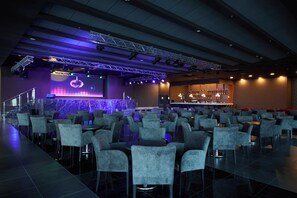 A conference room with rows of chairs, a stage with lighting equipment, and a bar area. - Secrets Sunny Beach Resort & Spa (Nessebar)