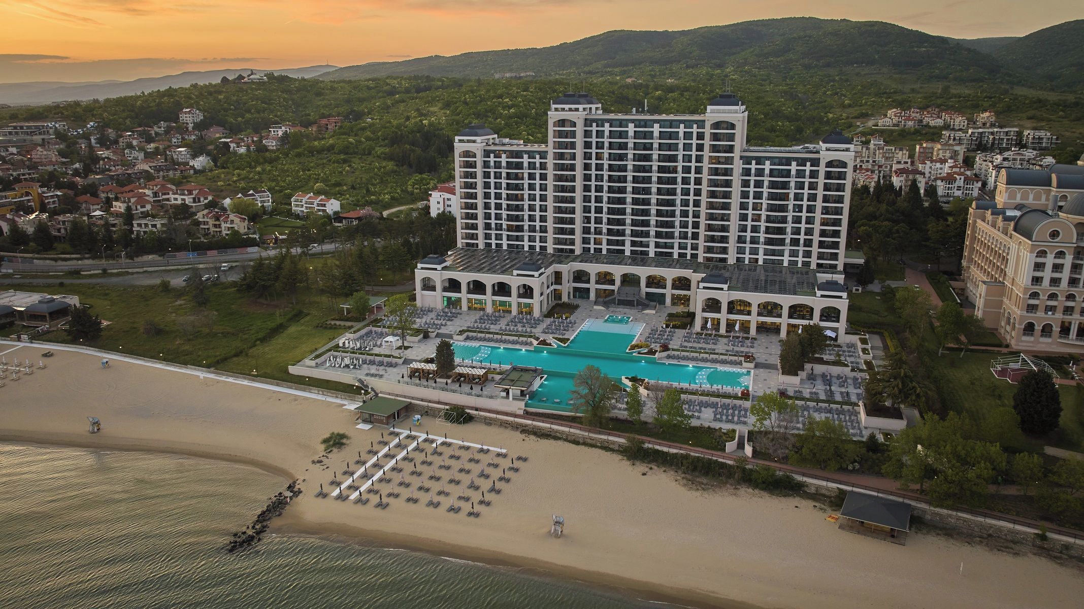 Um hotel com uma piscina grande, vários edifícios e uma área de praia.
