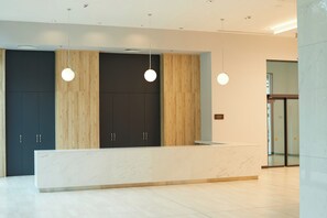 A reception desk with a marble top, wooden paneling, and pendant lighting. - Secrets Sunny Beach Resort & Spa (Nessebar)