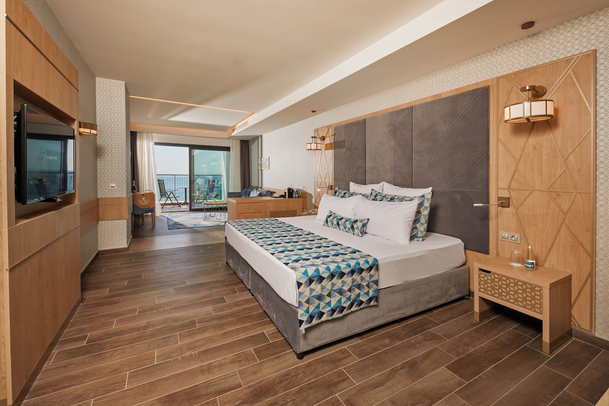 Une chambre d’hôtel moderne dotée d’un grand lit, d’une télévision, d’un balcon et d’un mur décoratif en bois.