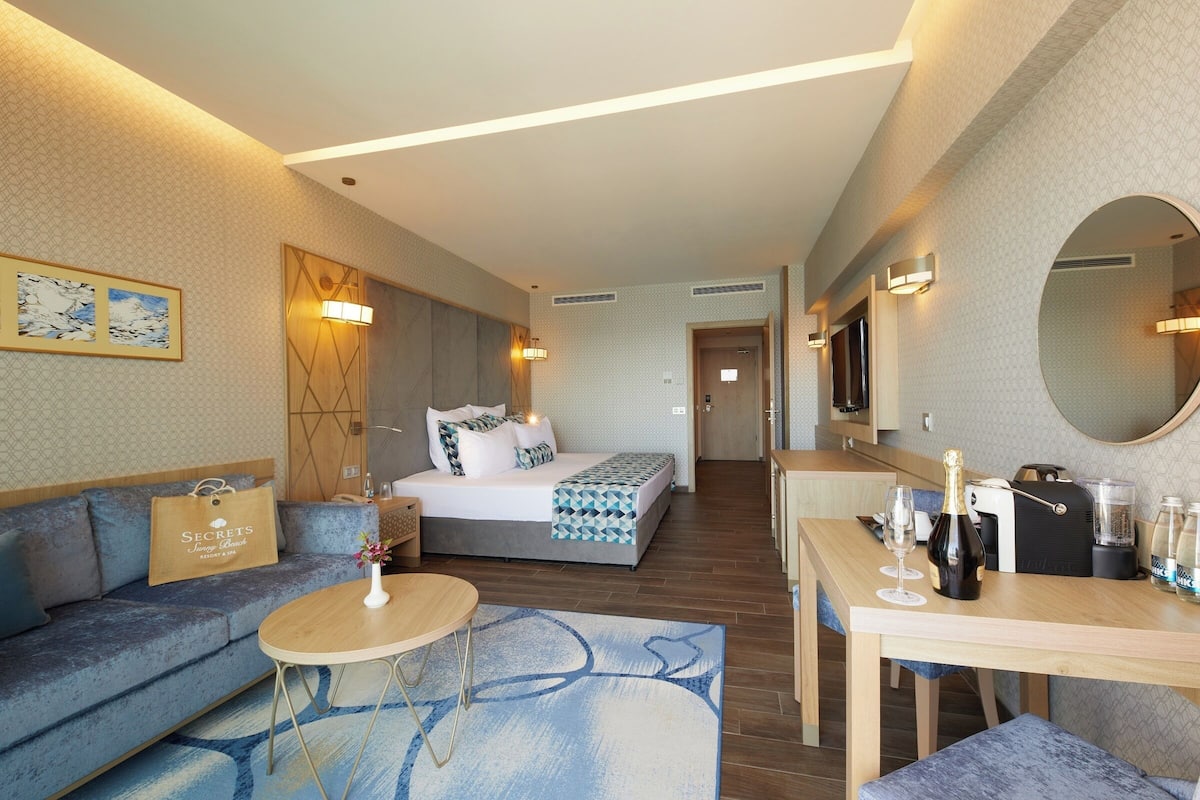 Une chambre d’hôtel moderne équipée d’un lit, d’un canapé, d’une table à manger et d’un petit coin cuisine.