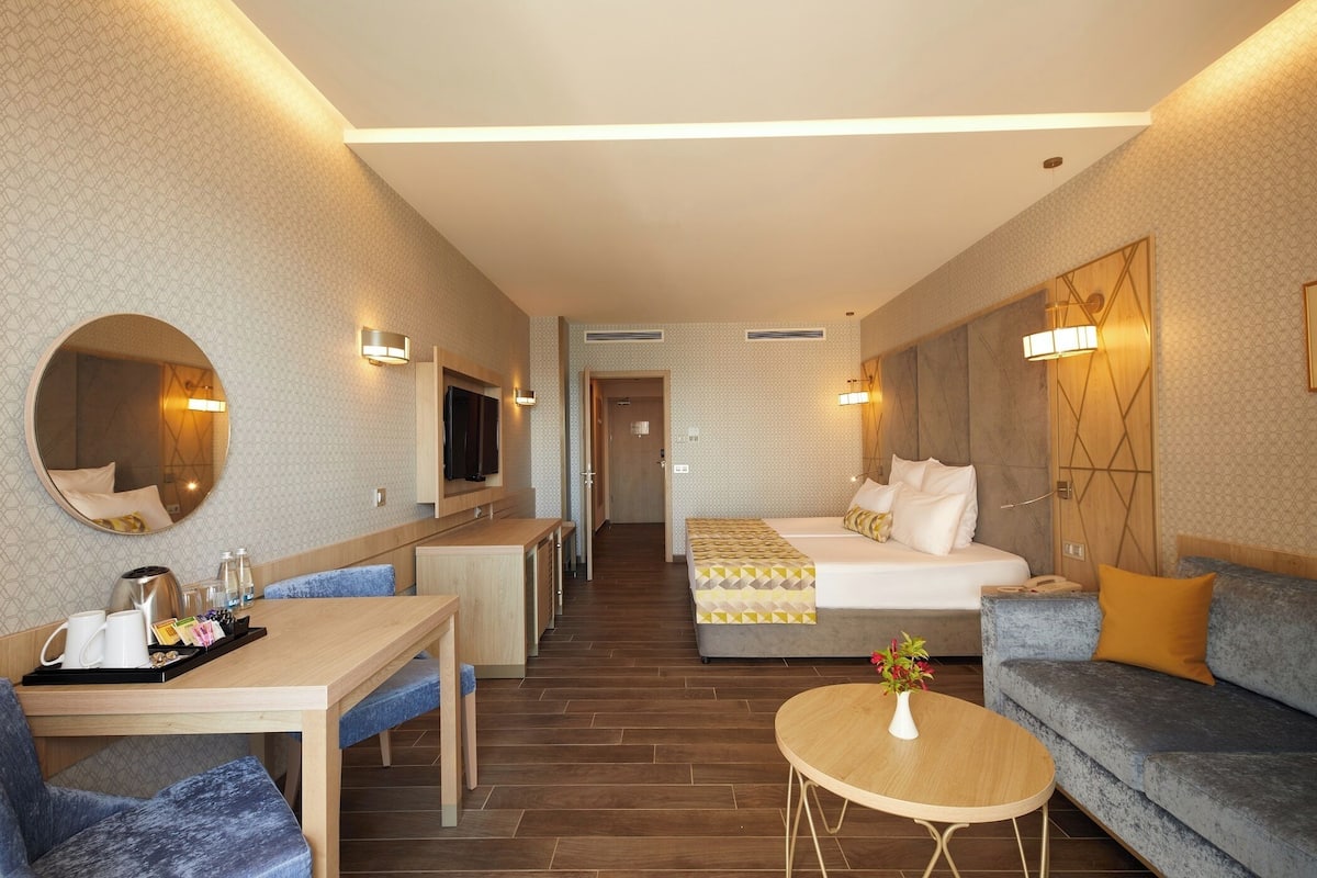 Une chambre d’hôtel avec un lit, un canapé, une table à manger et un téléviseur.