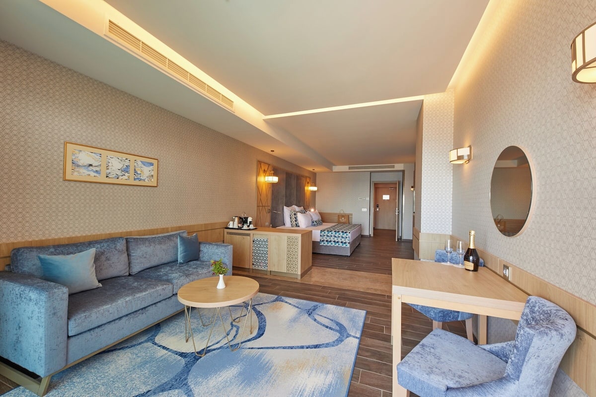 Une chambre d’hôtel moderne équipée d’un canapé, d’une table à manger, d’une petite table basse et d’un lit avec une table de chevet.