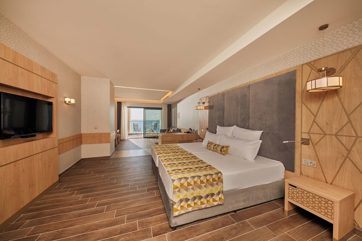 Une chambre d’hôtel moderne avec un grand lit, un téléviseur fixé au mur et une vue sur l’extérieur.