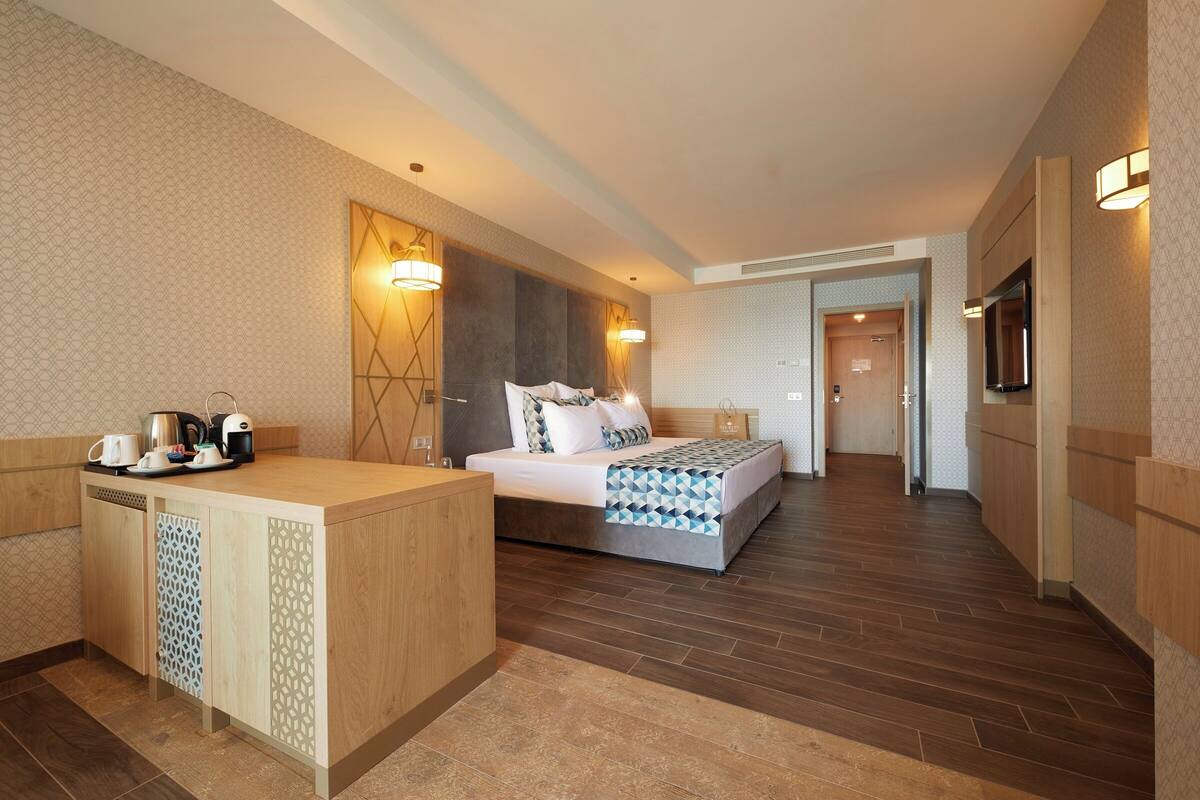 Une chambre d’hôtel avec un lit, une table de chevet et un petit coin cuisine.