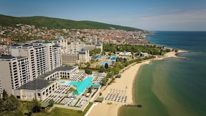 Un resort costero con varios edificios de gran altura, una amplia piscina y acceso directo a la playa.