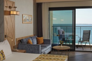 A hotel room with a bed, a sofa, a small table, a balcony with a view of the sea, and a wall-mounted light fixture. - Secrets Sunny Beach Resort & Spa (Nessebar)