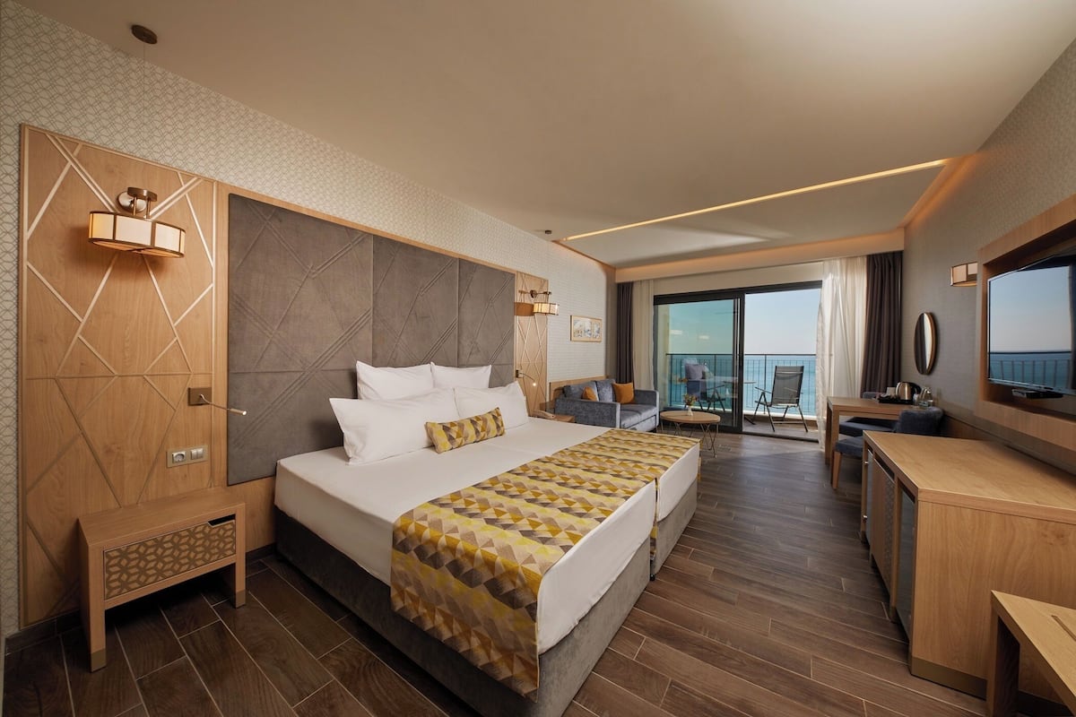 Une chambre d’hôtel avec un grand lit, un bureau, une télévision et un balcon avec vue.