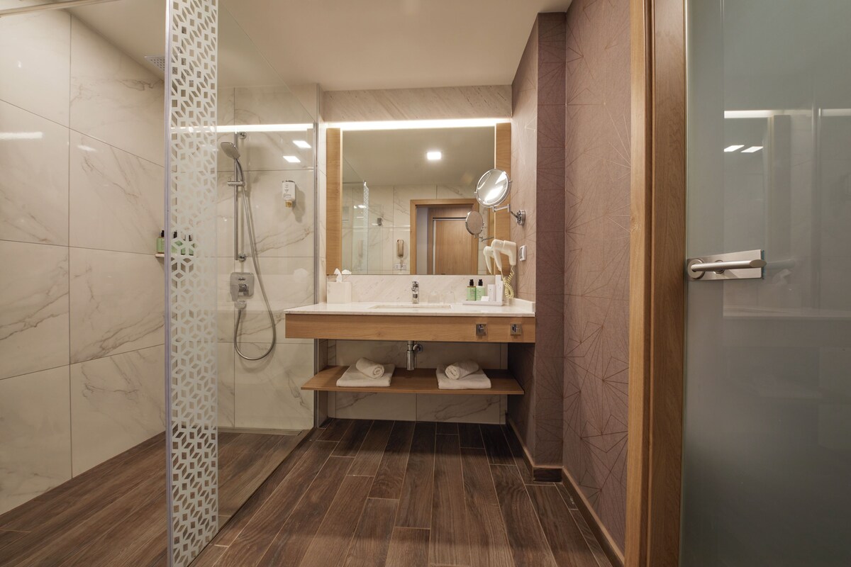 A modern bathroom with a shower, a sink with a mirror, and a towel rack.
