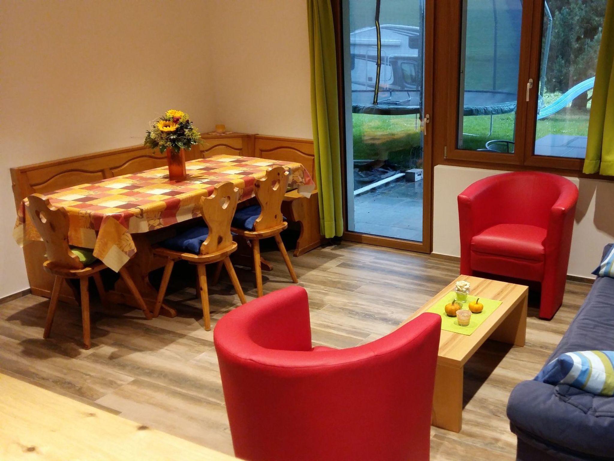 Un comedor con una mesa dispuesta para cuatro, una silla roja y un sofá.