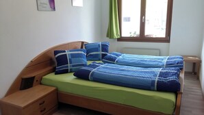 Una cama individual con cabecera de madera, una mesita de noche y una ventana con vistas al exterior.