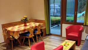 Una habitación con una mesa de comedor, sillas, un sillón rojo, un sofá y una ventana con vistas al exterior.