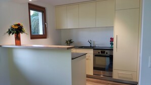 Una cocina moderna con una isla central, horno empotrado y ventana sobre el fregadero.