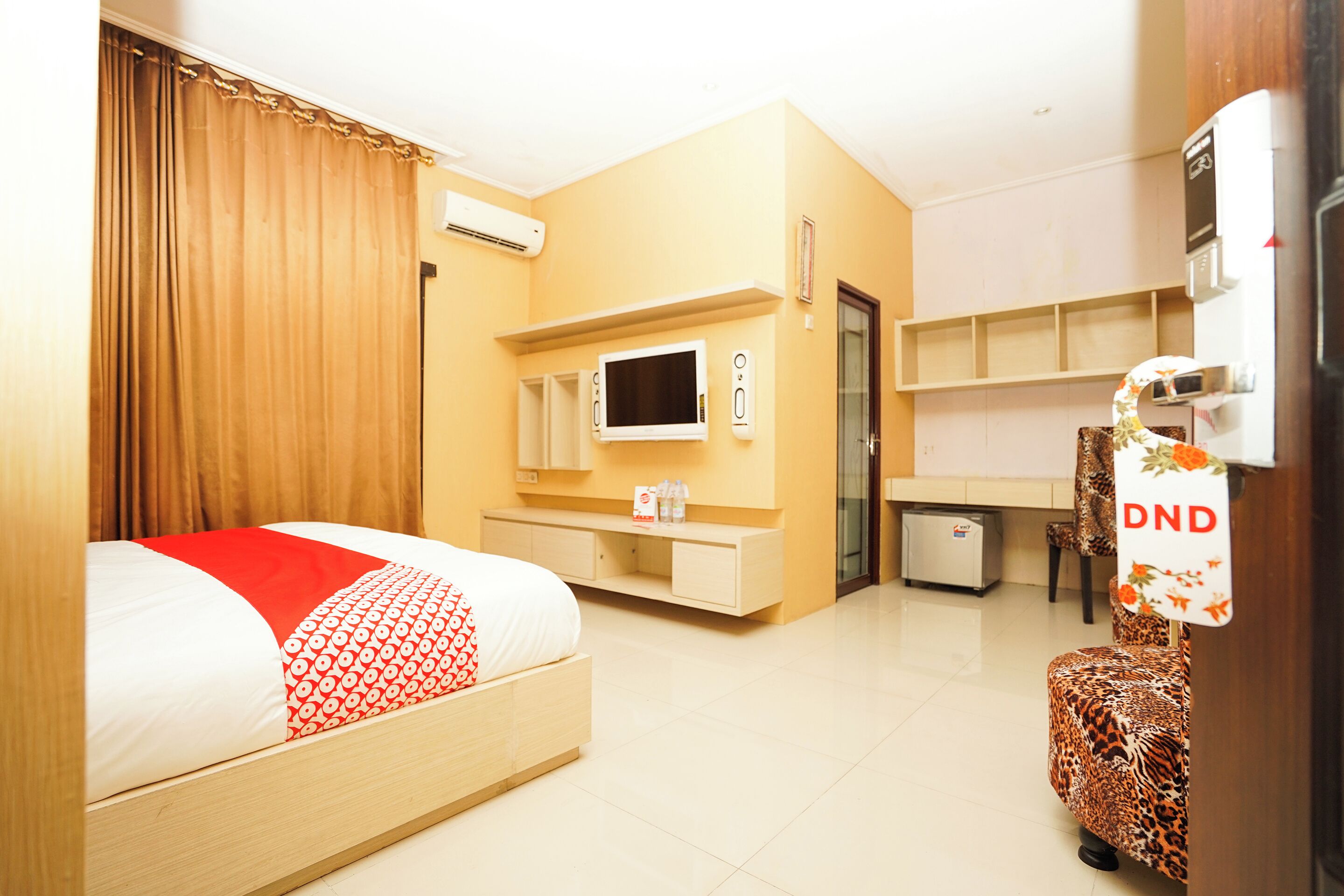 Una habitación de hotel con cama, escritorio, silla, televisión y minibar.