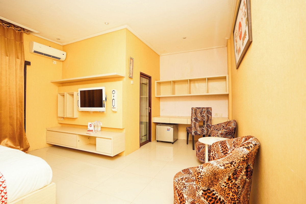 Una habitación de hotel con cama, televisión, escritorio, silla y refrigerador.
