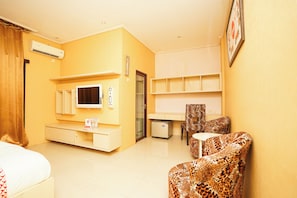 Una habitación de hotel con cama, televisión, escritorio, silla y refrigerador.