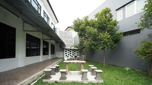 Un pati amb una taula d'escacs, bancs de pedra i un arbre petit.