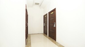 Un passadís amb dues portes de fusta, parets blanques i un sòl de rajoles.
