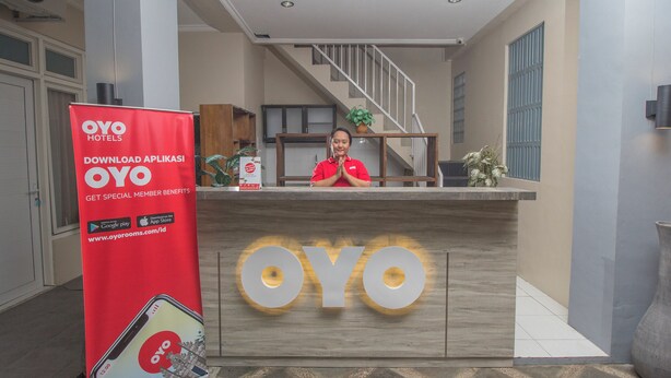 A hotel reception desk with a sign promoting a mobile app for special member benefits. - Irooms (Ngaglik)