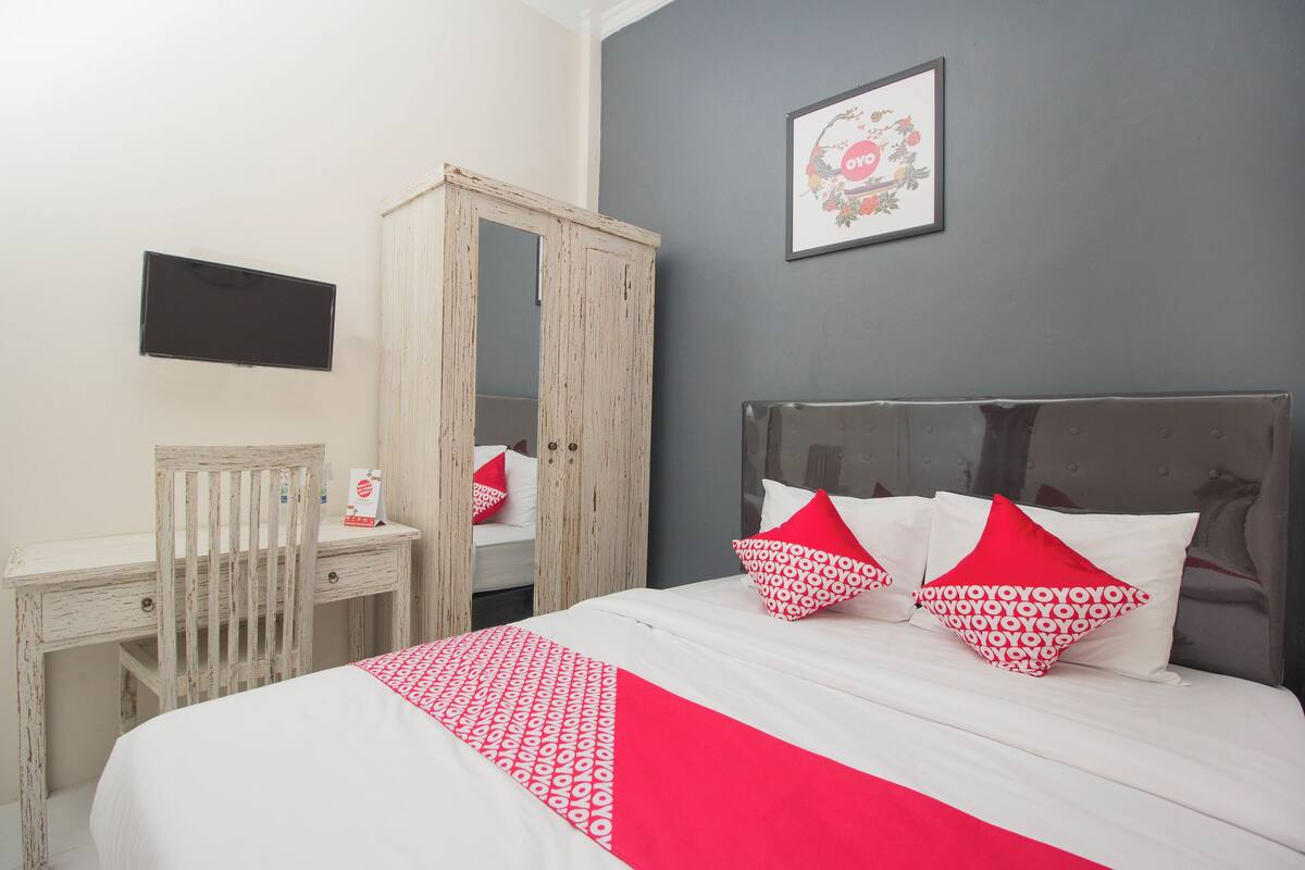 A bedroom with a bed, a desk, and a wardrobe.
