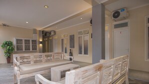 A room with a white bench, a small table, a potted plant, and a door marked with the letter 'E'. - Irooms (Ngaglik)