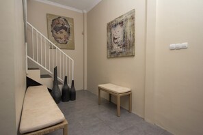 A hallway with a bench, a staircase, and two paintings on the walls. - Irooms (Ngaglik)