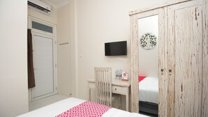 A bedroom with a bed, a desk, a chair, a wardrobe, a television, and a wall decoration. - Irooms (Ngaglik)