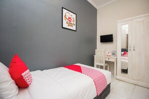 A bedroom with a bed, a desk, a wardrobe, and a television on the wall. - Irooms (Ngaglik)
