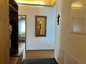 Ein Korridor mit Holzboden, einem Spiegel an der Wand und einem Kreuz als Dekoration.